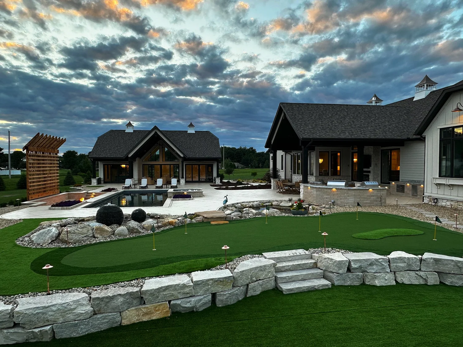 Backyard putting green and boulder wall at sunset built by RC Outdoor