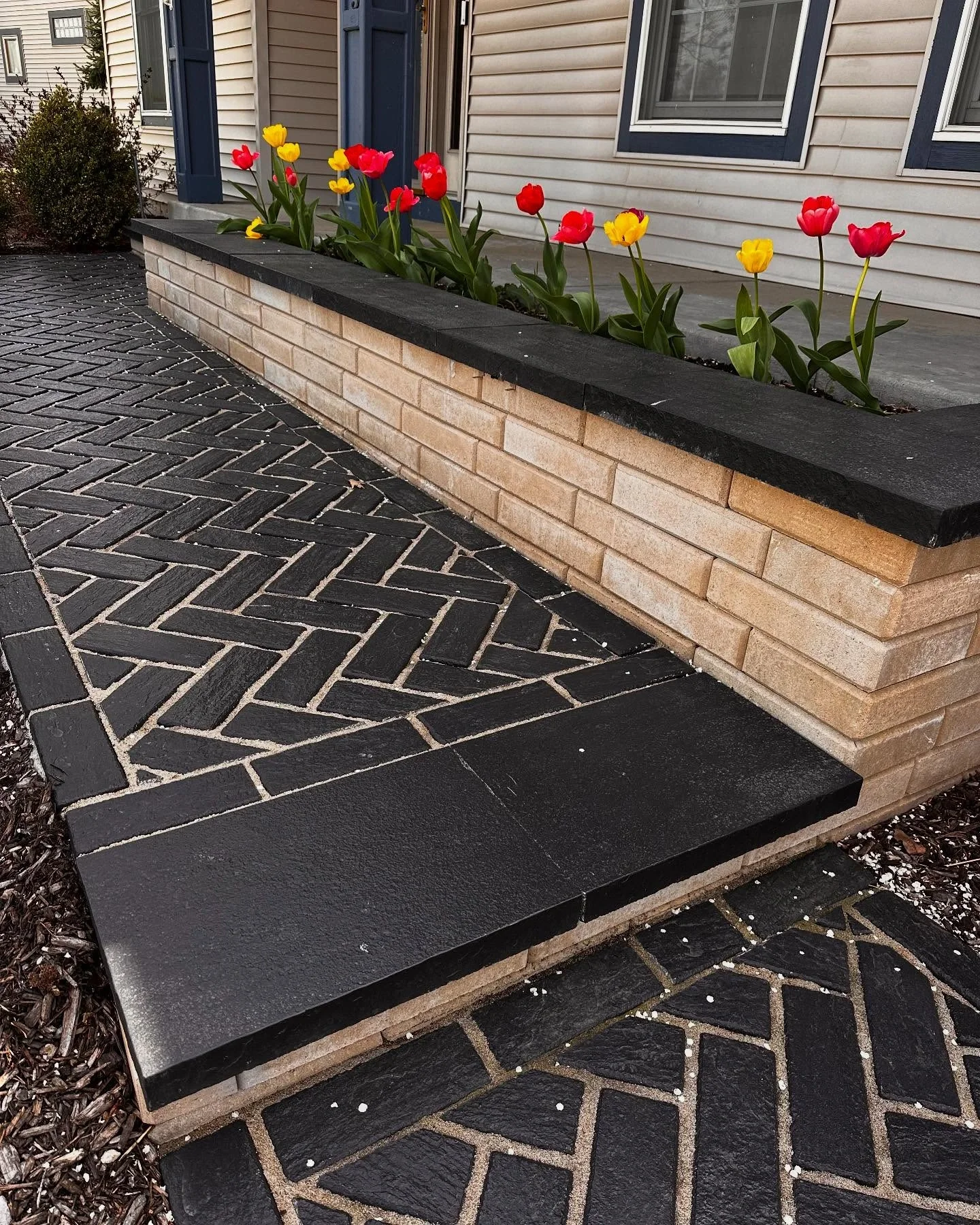 Dark paver step with a herringbone landing and planter wall