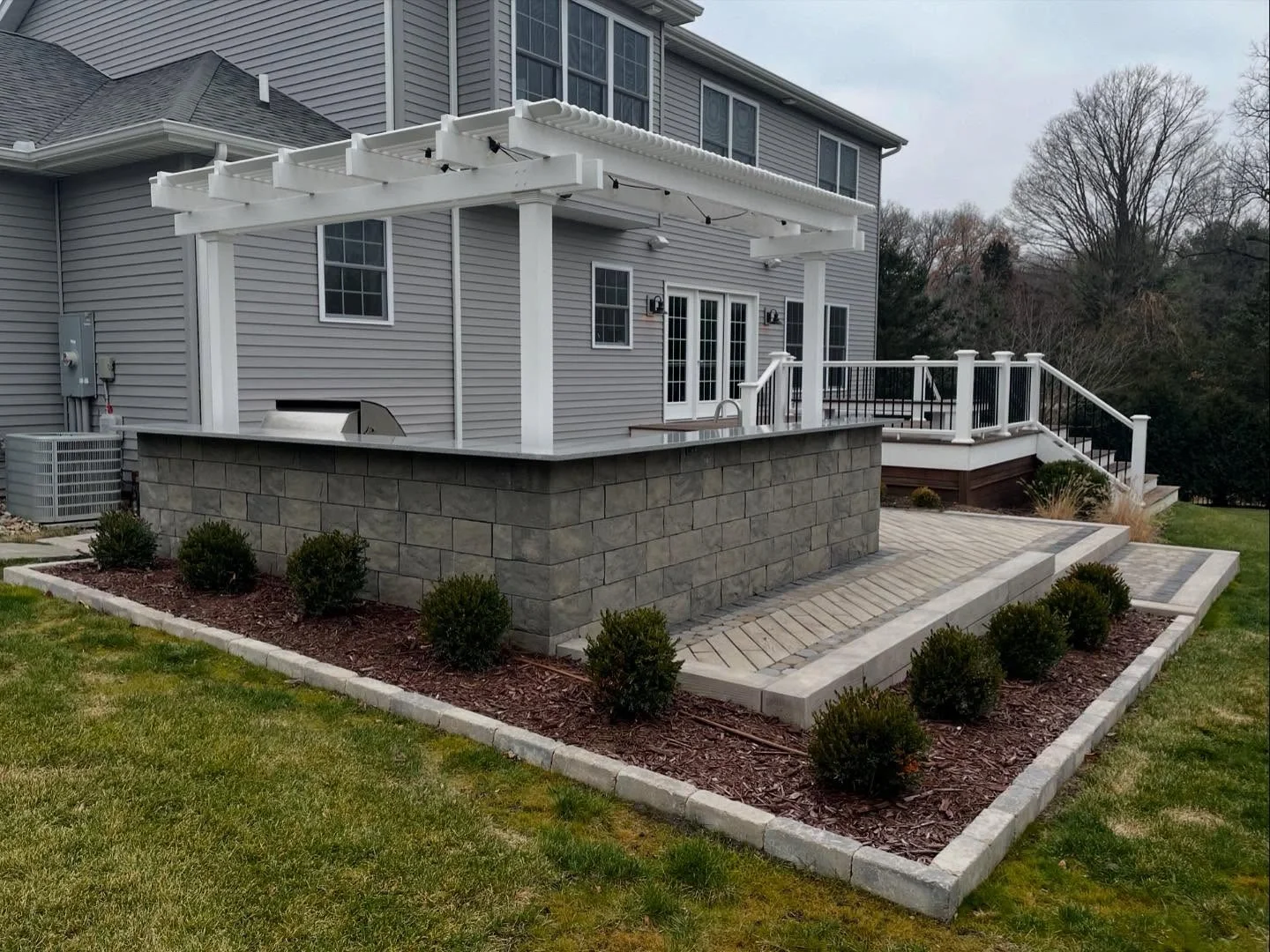 Steps from a raised deck down to a paver patio built by RC Outdoor