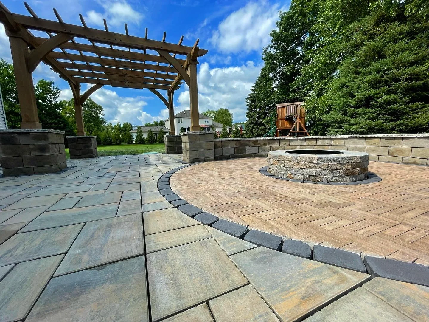 Pergola beside a curved paver patio with a fire pit