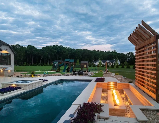Pool with a fire feature and privacy pergola at dusk