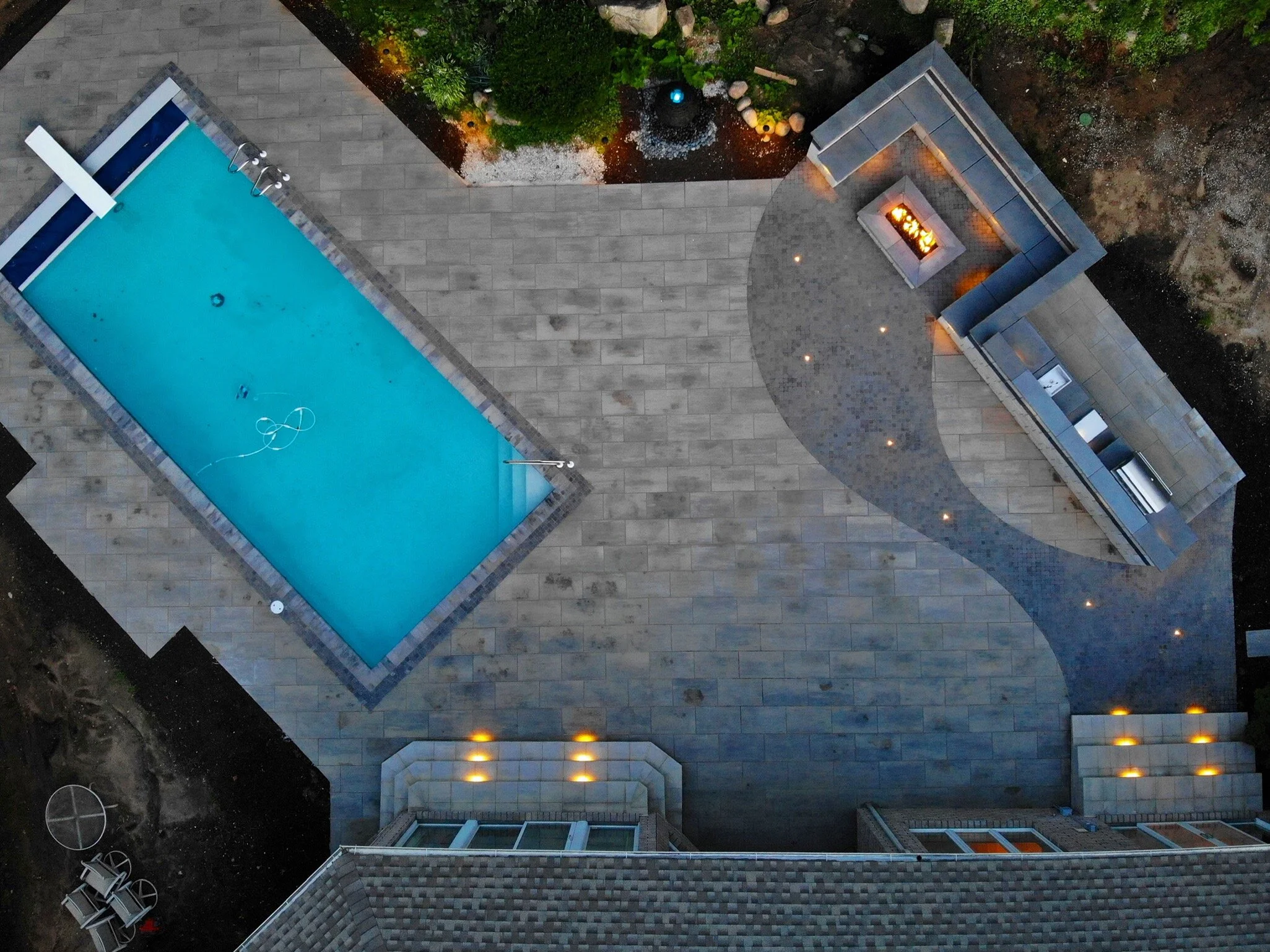Aerial view of a pool with a paver patio and outdoor kitchen